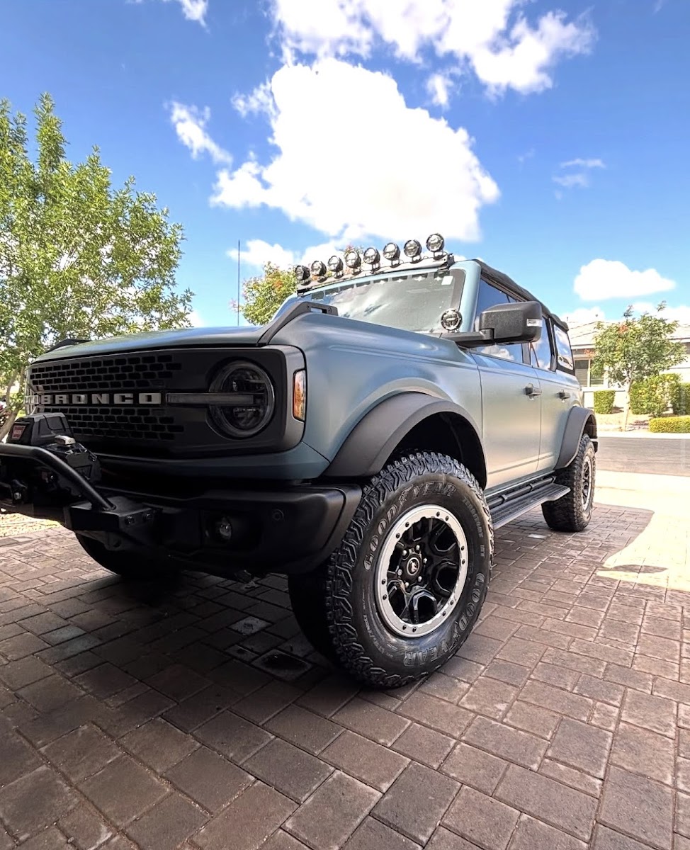 Lifted matte-blue Ford Bronco Badlands, off-road setup, Phoenix sun